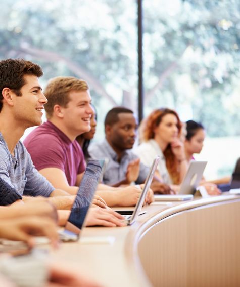 Estudiantes en un aula universitaria tomando apuntes con portátiles